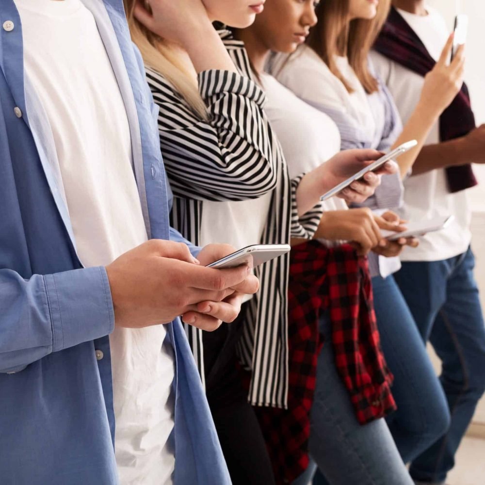 Social networks. Friends texting on their smartphones, standing in row